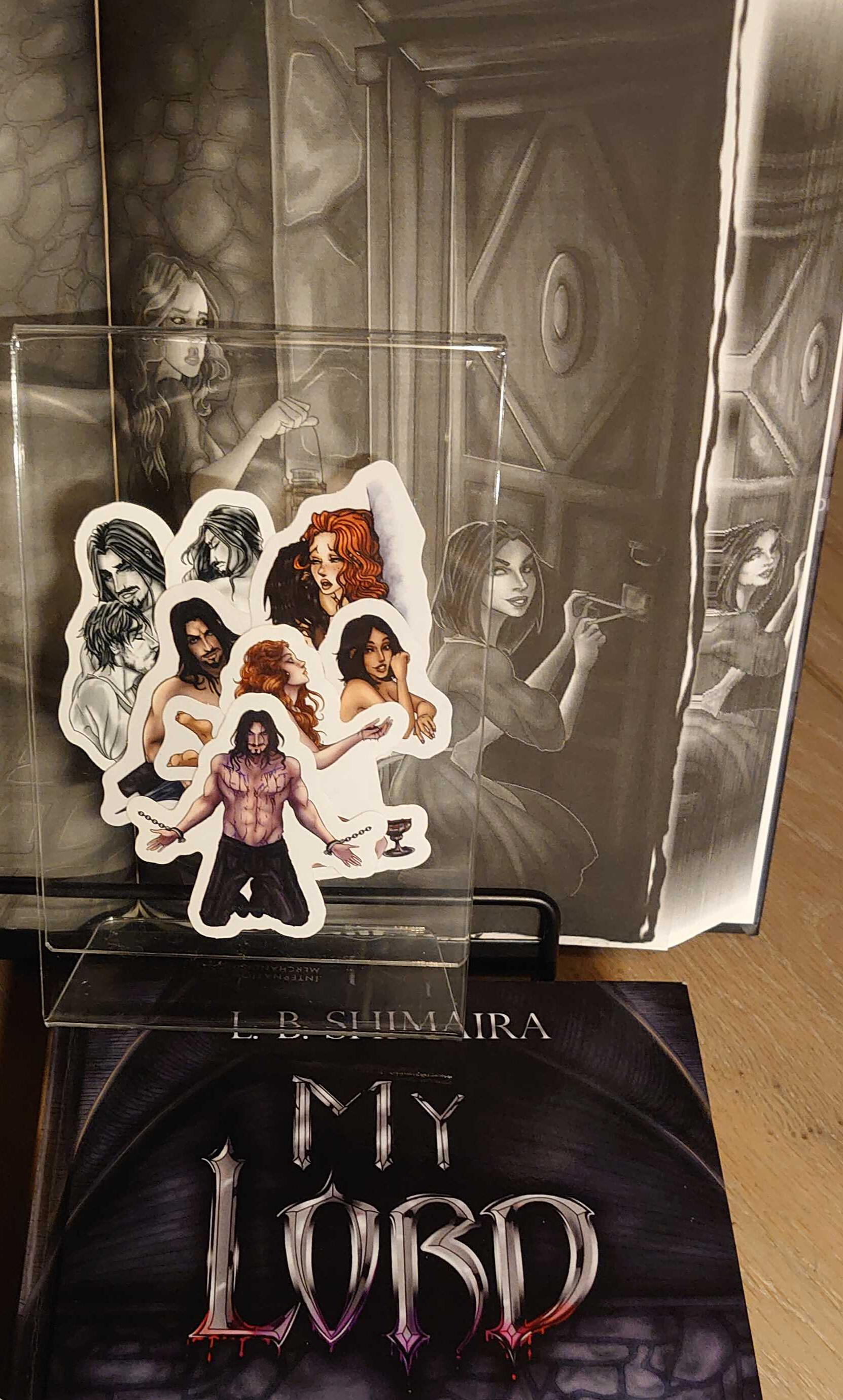 Photo showcasing internal art and the printed edge. The printed edge is the same as the art, which features a woman kneeling to lockpick a door. There is also a collage visible of 7 stickers with character art.